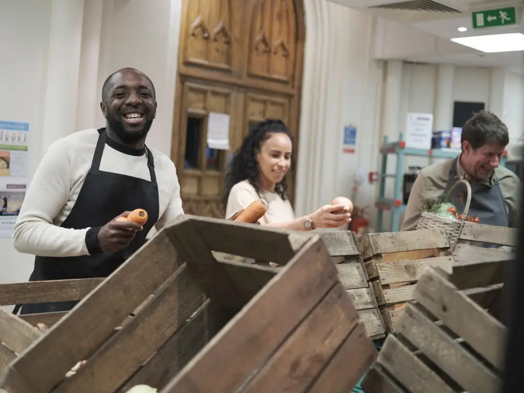 three people volunteering in their community smiling and moving boxes and healing through safe spaces